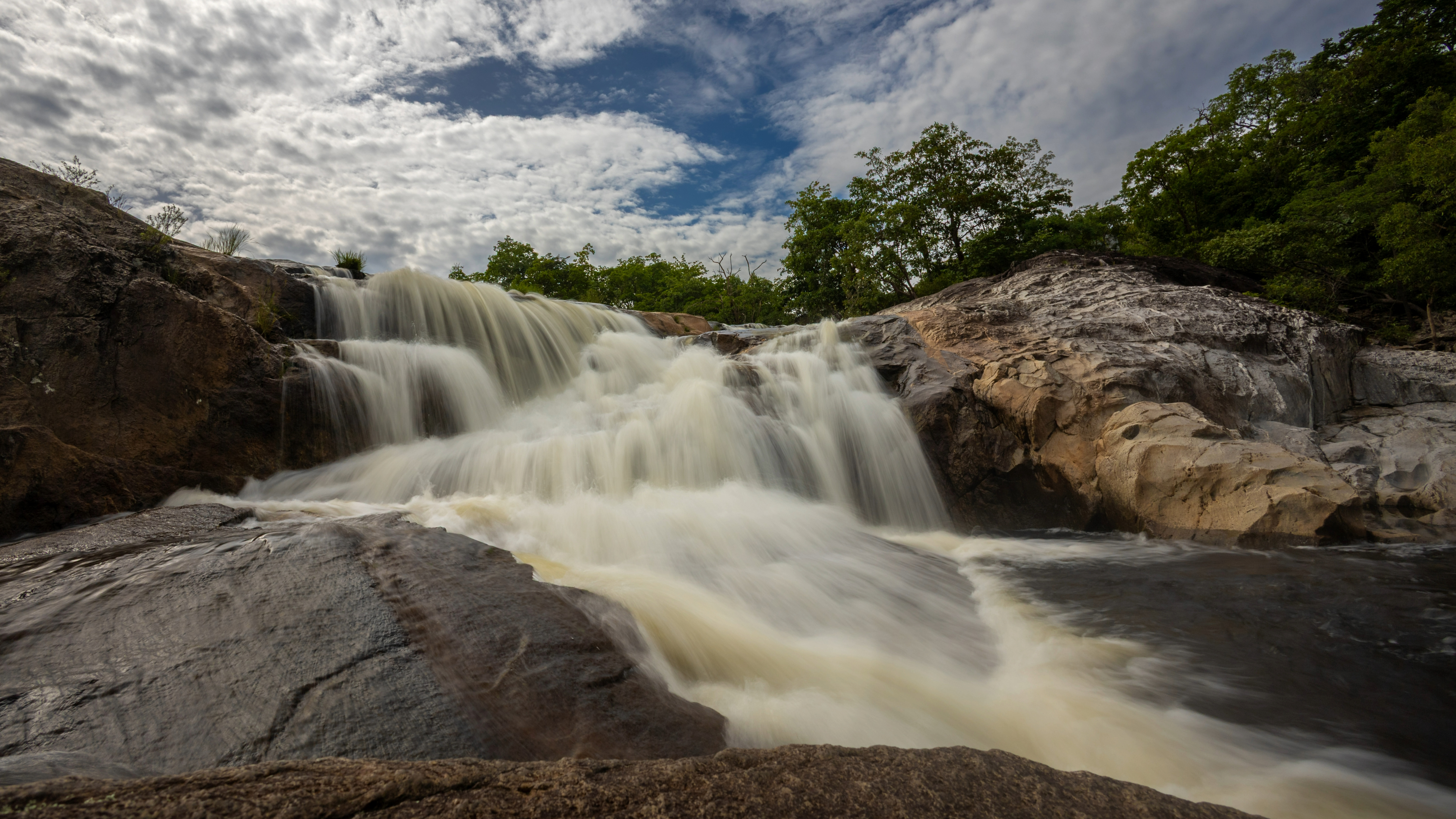 Cachoeira São Bartolomeu, com água corrente sobre pedras claras próxima à Chácara Cajuí